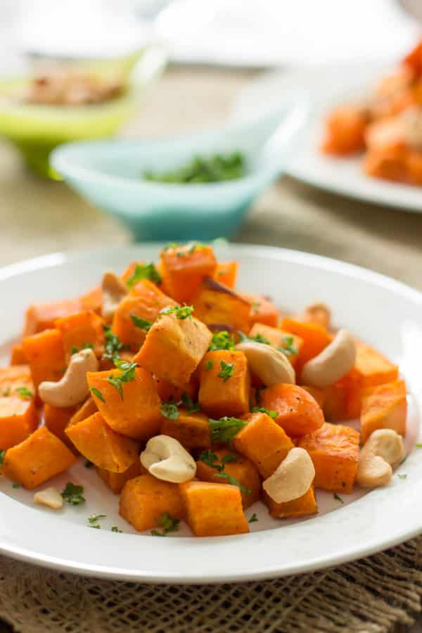 Baked Sweet potato with cashews on a white plate.