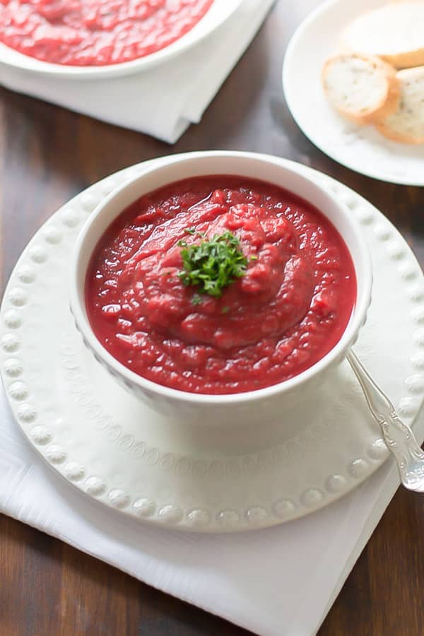 Beet Sweet Potato Soup in a white bowl with parsley on top 