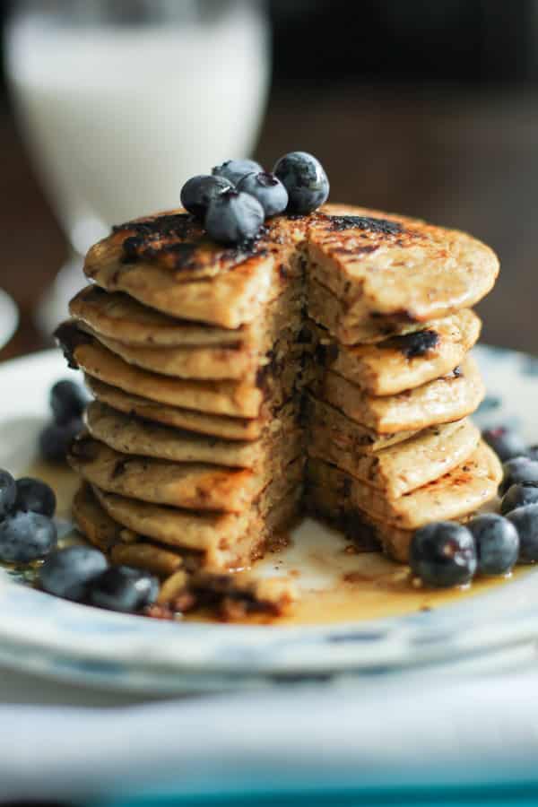 A stack of peanut butter and chocolate chips pancake with blueberries on top, cut opened.