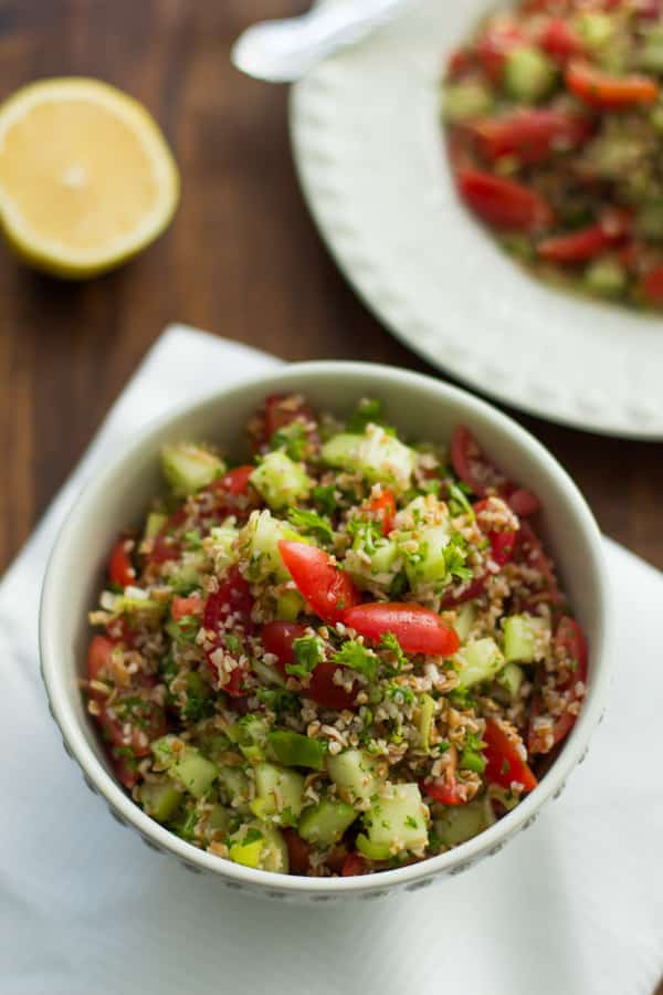 bowl of tabbouleh with bulgur, cherry tomatoes, cucumber, mint, and parsley 
