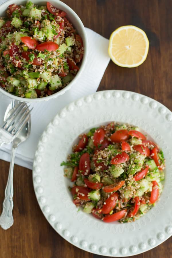 Plate and bowl of Tabbouleh made with bulgur, cherry tomatoes, cucumbers, parsley, mint, and scallions