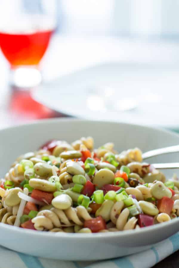 close up of pasta salad with lima beans and anchovies topped with sliced scallions