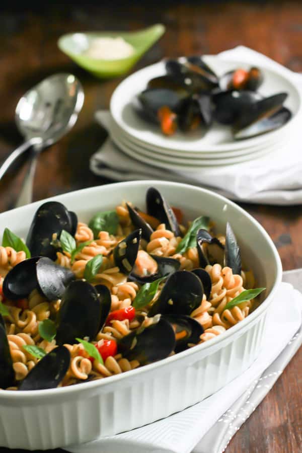 Close up of Whole Wheat Fusilli with Mussels with a plate of mussels in the background