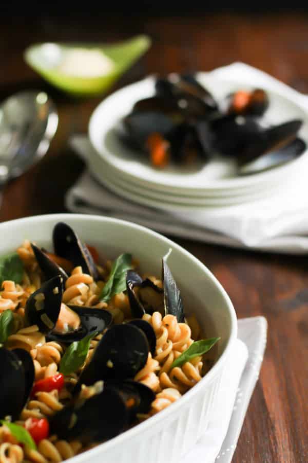 Close up of Whole Wheat Fusilli with Mussels with a plate of mussels in the background