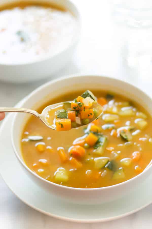 A bowl of summer soup with peas, carrots and zucchini.