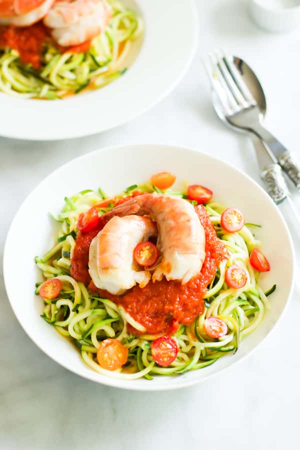 Zucchini noodles with tomato sauce and shrimp in a white bowl