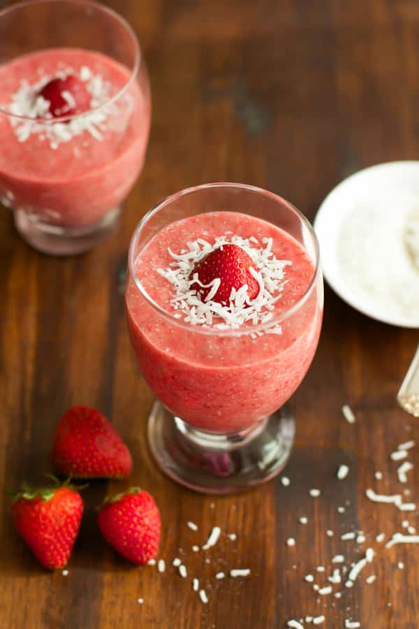 Two servings of strawberry chia pudding topped with shredded coconut and a strawberry.