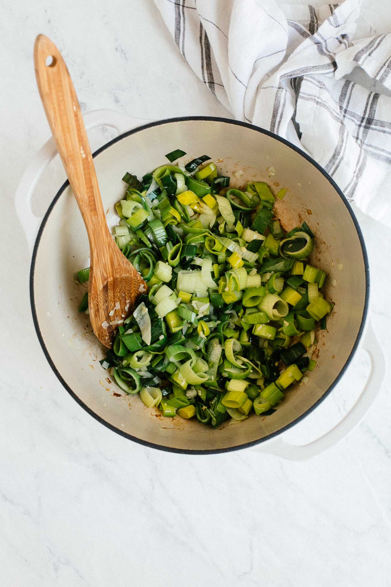 Leeks being sautéed in a dutch oven.