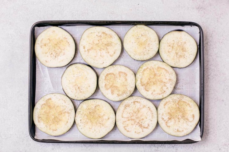 raw slices of eggplants on a baking sheet
