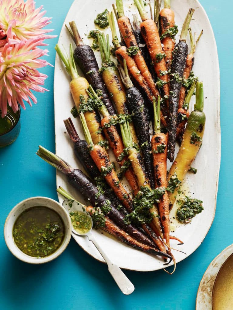 A white platter of charred carrots with basil and mint.