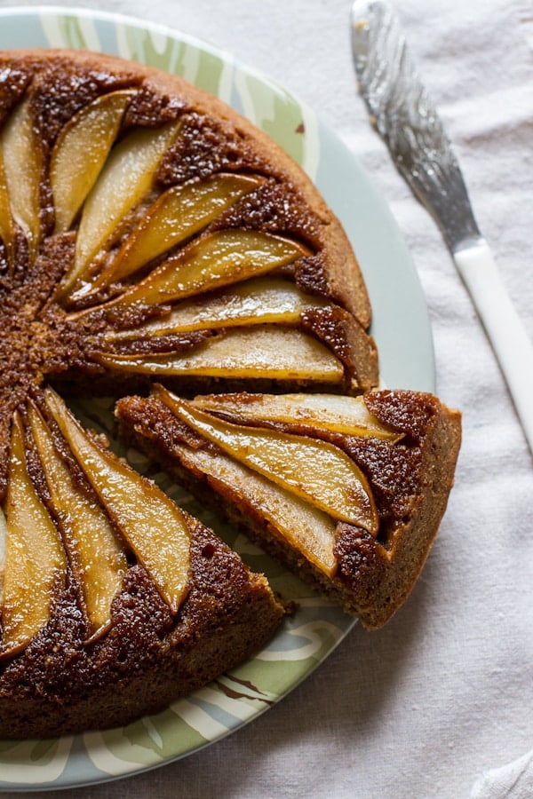 A close up of a buttermilk pear upside-down cake with a slice cut out.