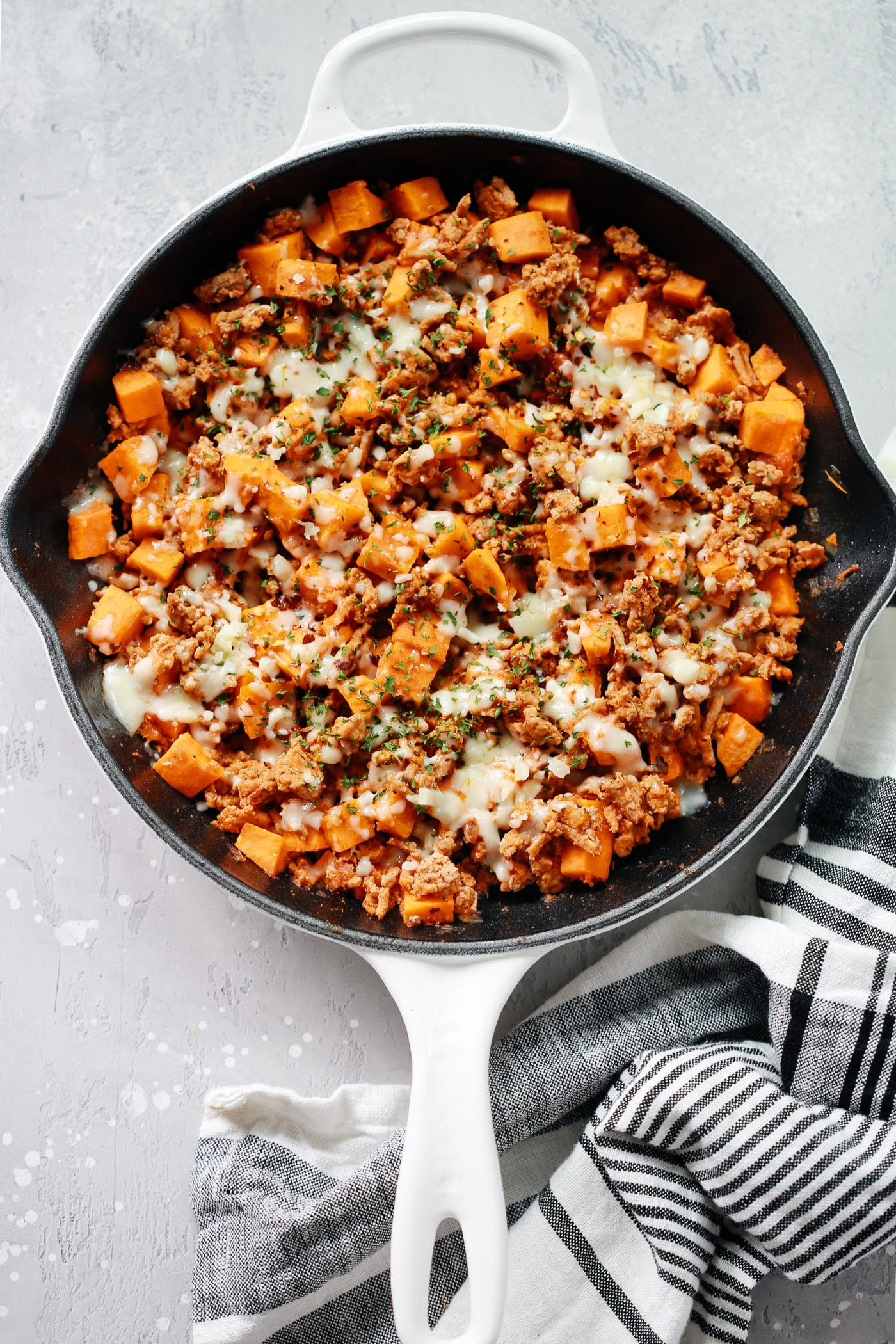 A white cast iron with ground turkey and sweet potatoes.