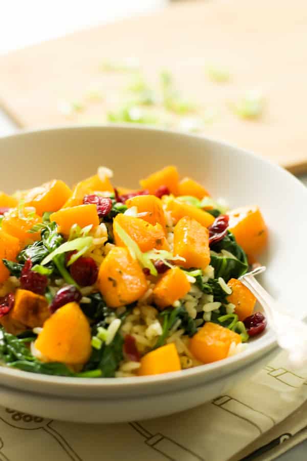 An angle photo of rice with roasted butternut squash and dried cranberries in a bowl.