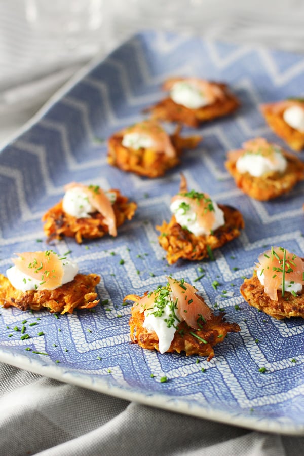 A blue platter with multiple sweet potato latkes with Greek yogurt and smoked salmon.