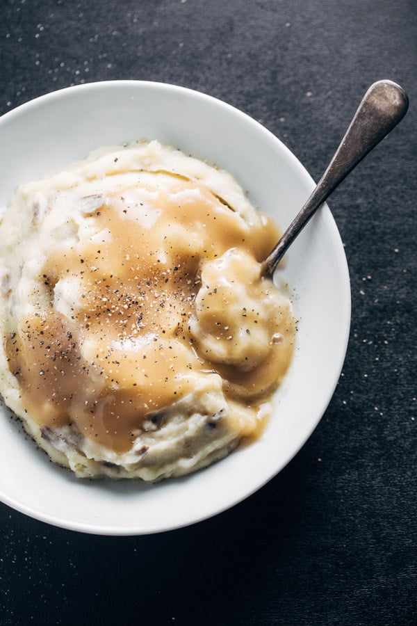 A bowl of garlic mashed potatoes with gravy on top.