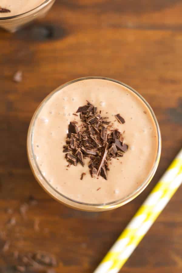 An overhead image of a cup of chocolate peanut butter smoothie with shaved chocolate on top.