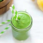 overhead view of a green smoothie in a mason jar with a straw