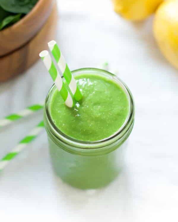 overhead view of a green smoothie in a mason jar with a straw