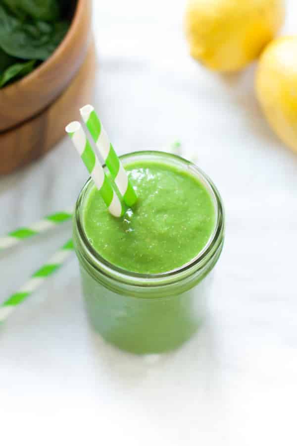 overhead view of a green smoothie in a mason jar with a straw