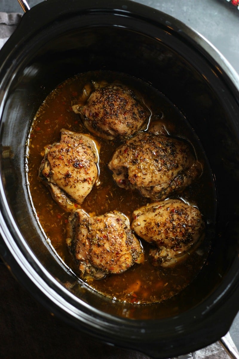 overhead view of a slow cooker pot containing jerk chicken 