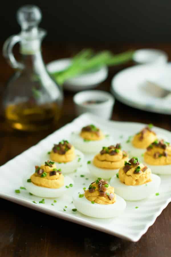 An angled photo of a platter of lentil deviled eggs with chives on top.