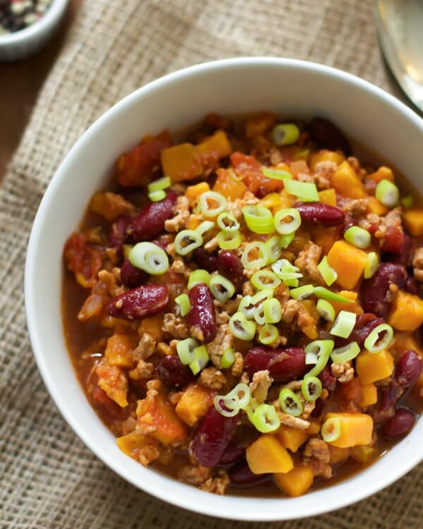 Slow cooker sweet potato chili in a white bowl with green onions on top.