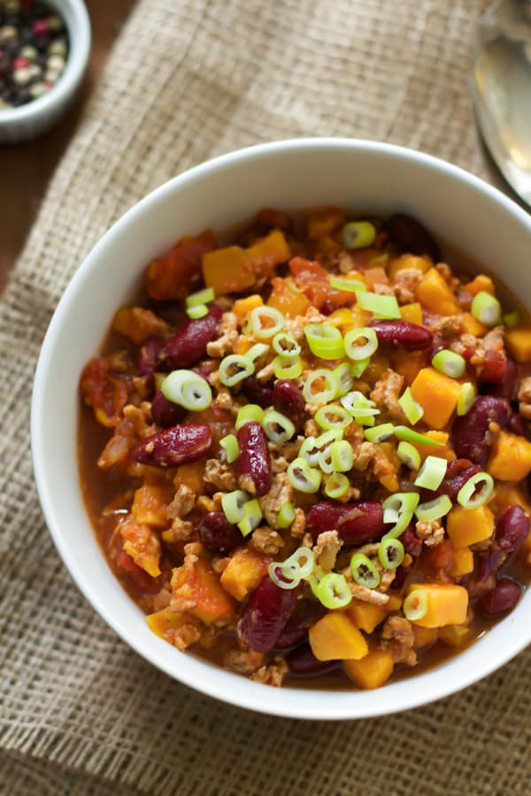 Slow cooker sweet potato chili in a white bowl with green onions on top. 