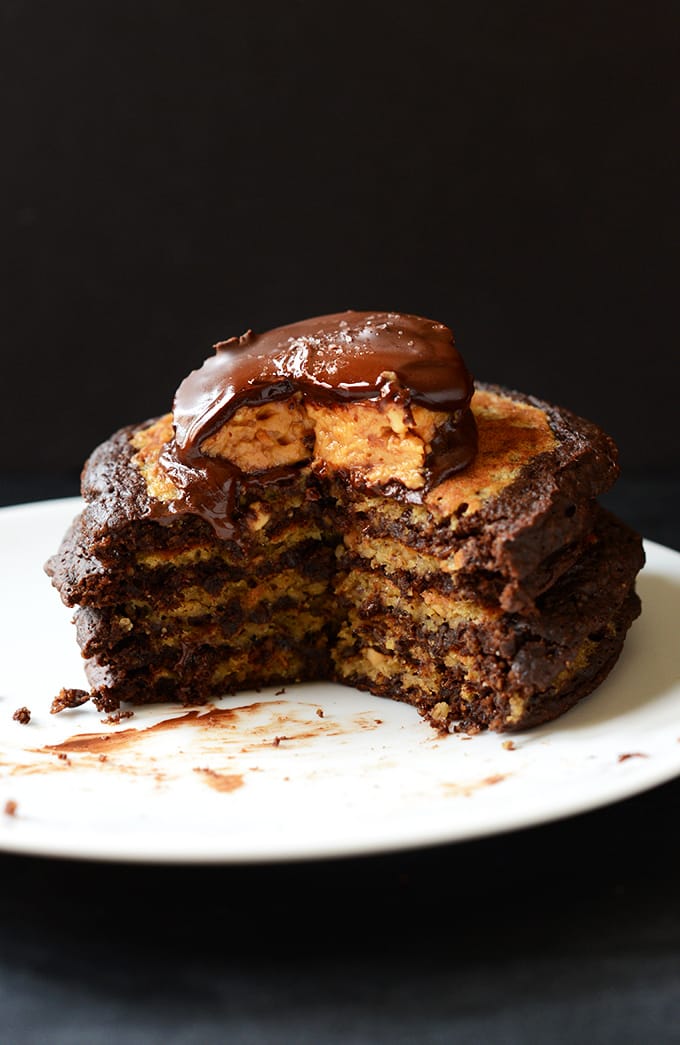 Chocolate-Peanut-Butter-Cup-Pancakes- A stack of chocolate peanut butter cup pancakes with a large wedge cut out of them.