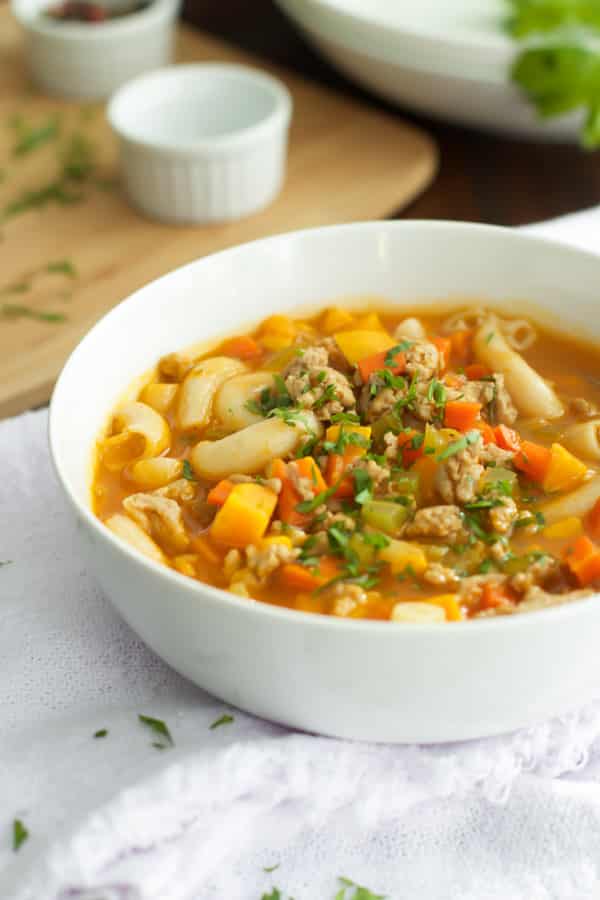 A white bowl with ground turkey pasta soup inside.