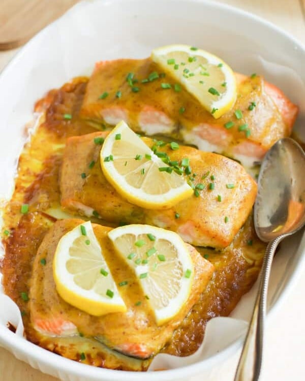 A close up of maple mustard salmon with sliced lemon on top.