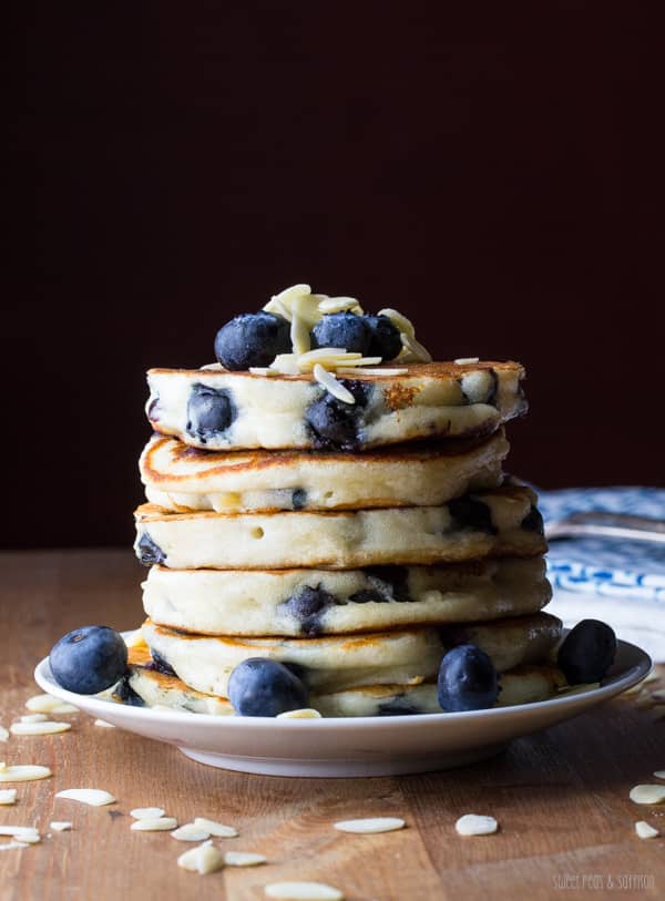 A stack of blueberry almond pancakes with whole blueberries and sliced almonds on top.