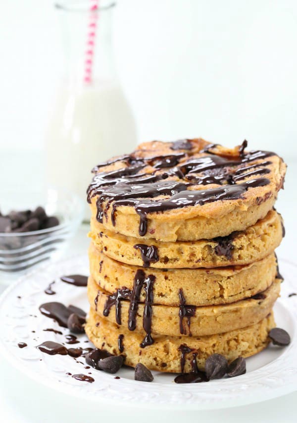 A stack of five whole wheat chocolate pancakes drizzled with chocolate sauce.