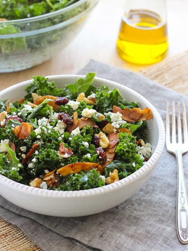 Kale salad with vegan coconut bacon in a white bowl.