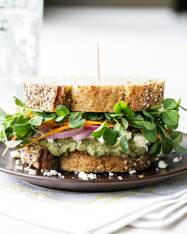 A side view of a Mediterranean Loaded Veggie Sandwich on a black plate.