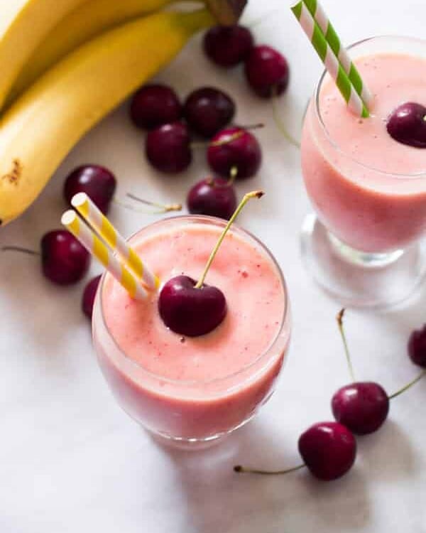 Overhead photo of two glasses of cherry pineapple smoothies.