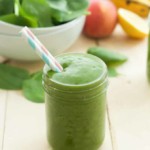 close up of a green smoothie in a mason jar with a straw