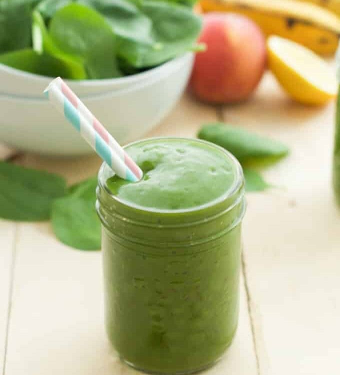 close up of a green smoothie in a mason jar with a straw