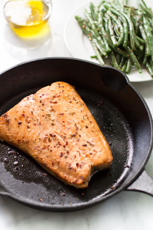 A skillet containing a broiled salmon.