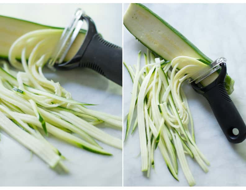Zucchini being sliced with a vegetable peeler.