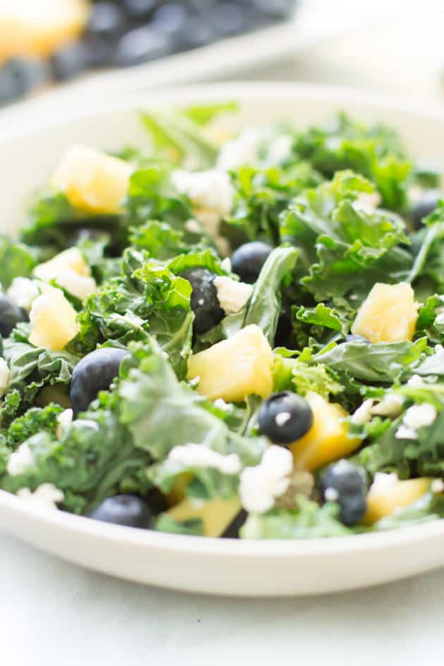 Close up photo of a bowl of blueberry pineapple kale salad.
