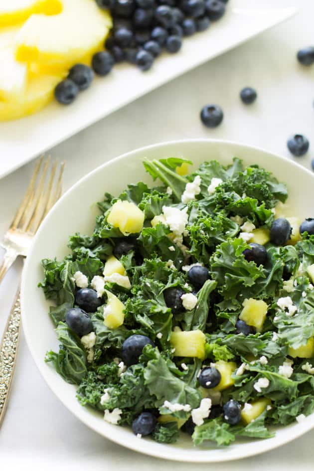 A bowl of kale blueberry pineapple salad.