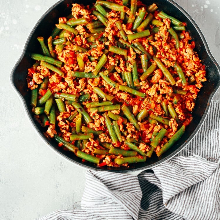 overhead view of a white skillet containing green beans and ground turkey