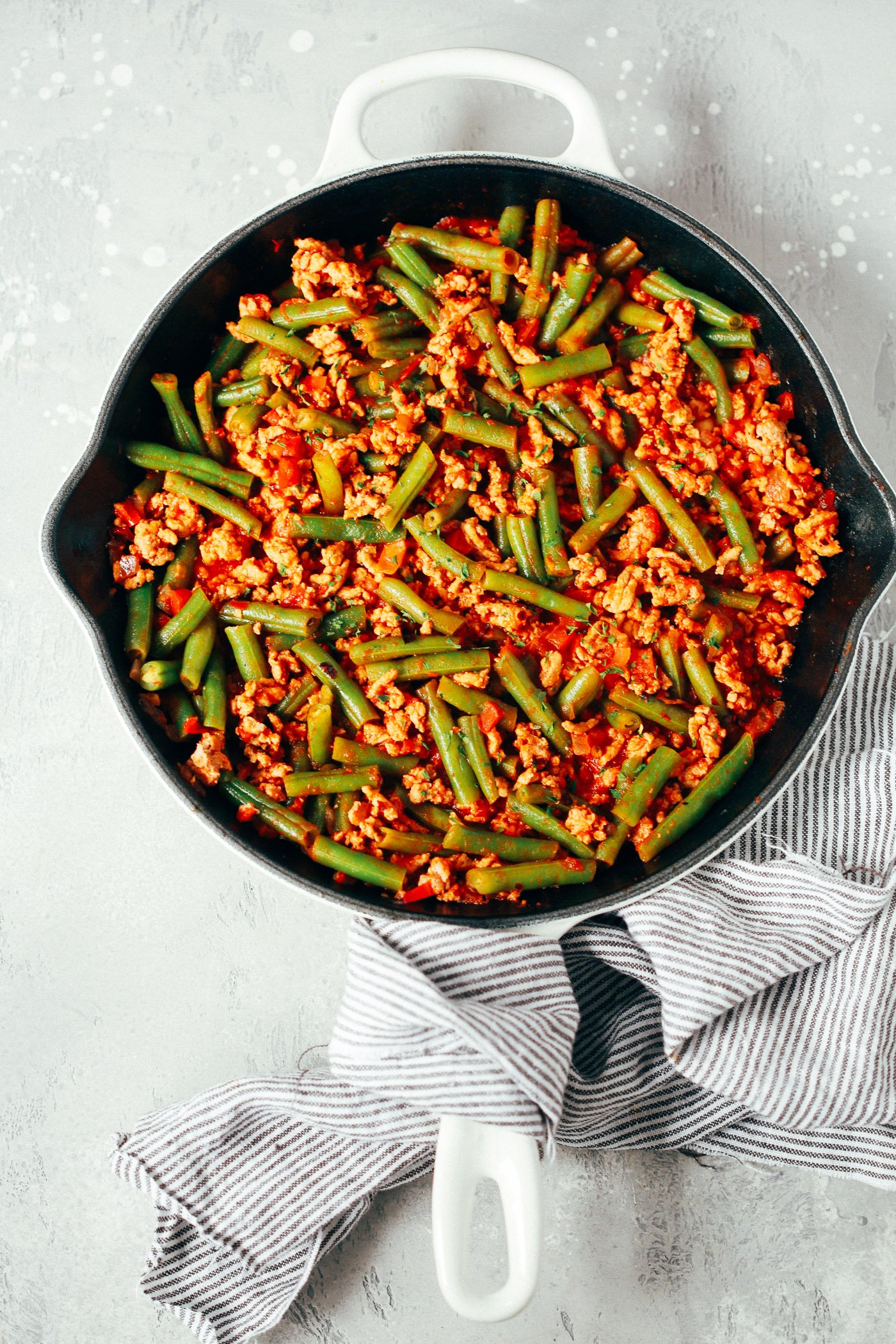 overhead view of a white skillet containing green beans and ground turkey