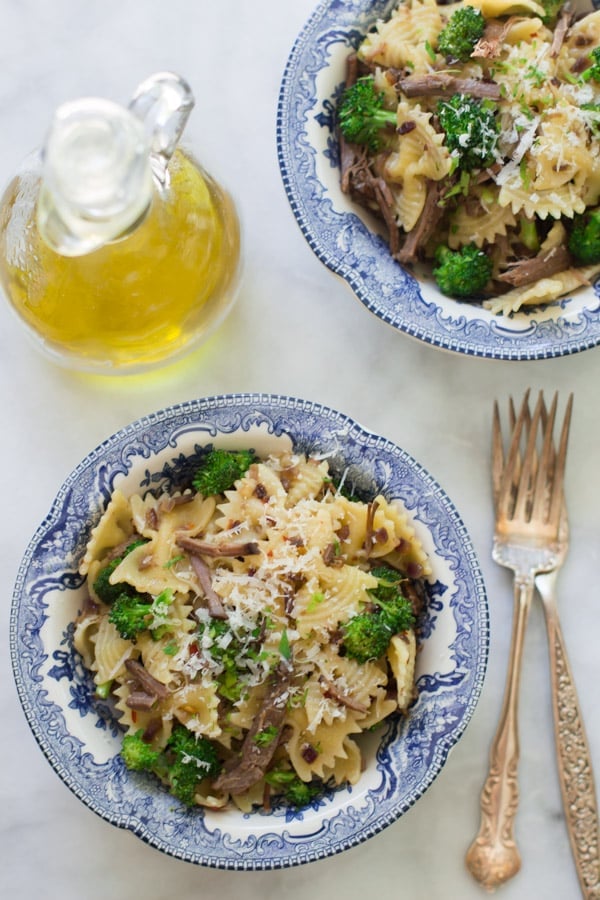 Two bowls of leftover shredded roast beef pasta with two forks.