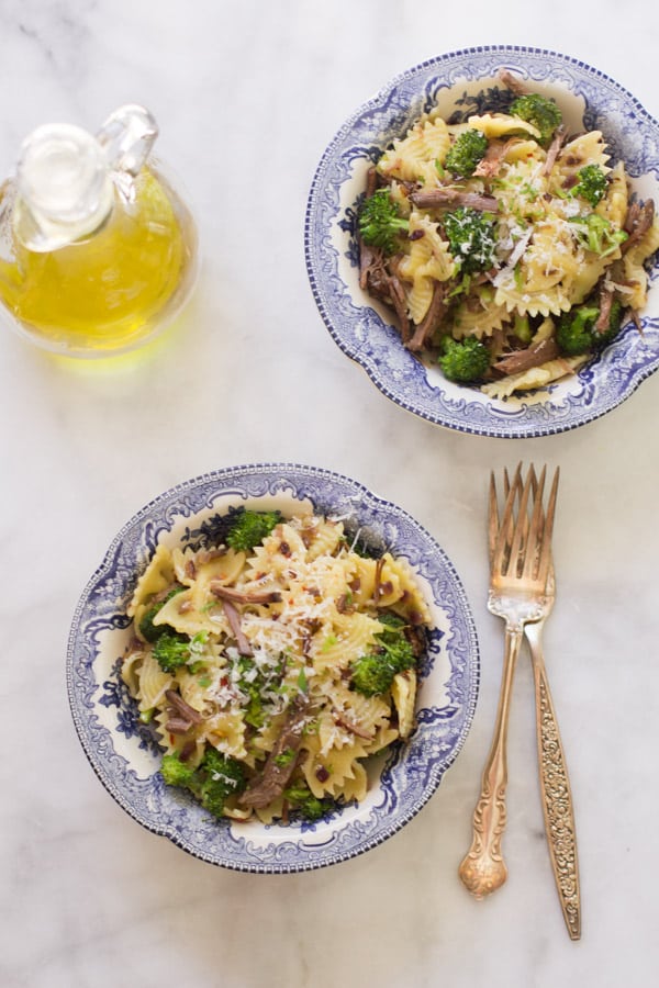 Two bowls of pasta with leftover shredded roast beef.