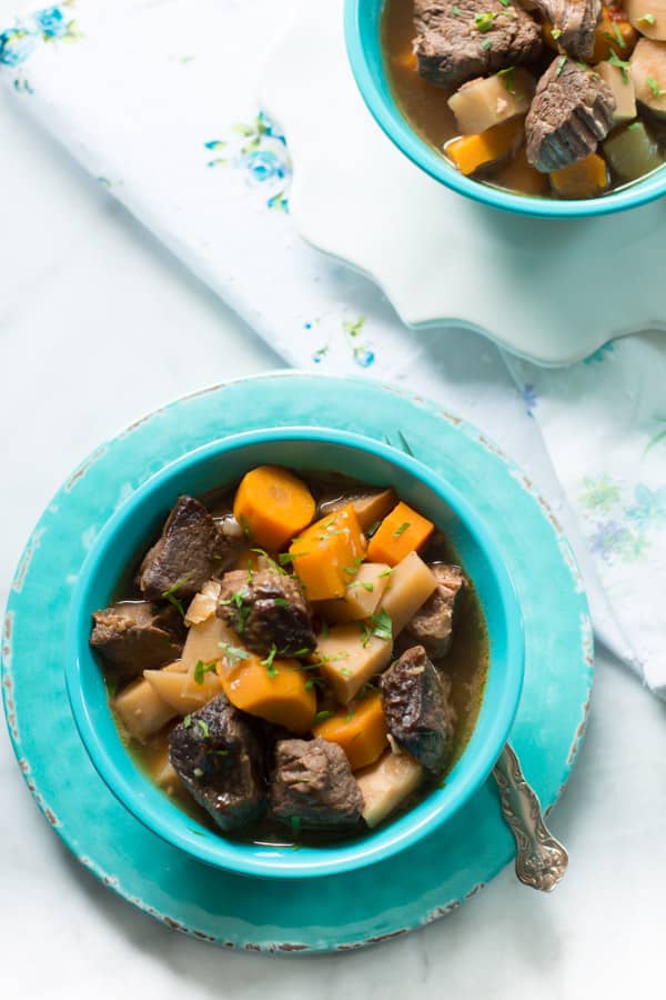 A blue bowl of turnip and carrot slow cooker beef stew.