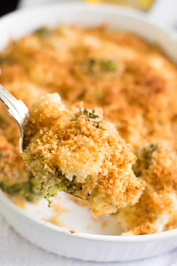 A close up of a spoonful of cheesy broccoli cauliflower.