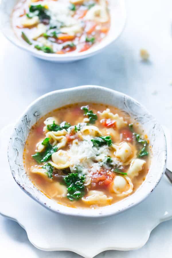 A bowl of kale tomato tortellini soup.