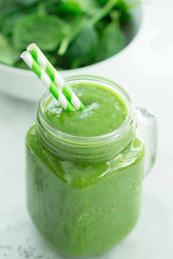 green smoothie in a mason jar with a straw 