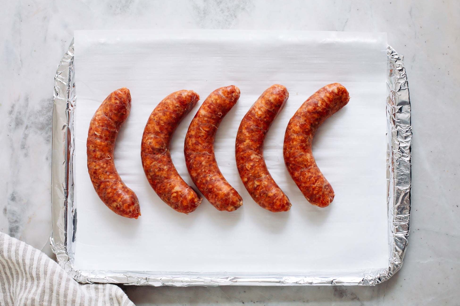 A lined sheet pan with sausage on it.